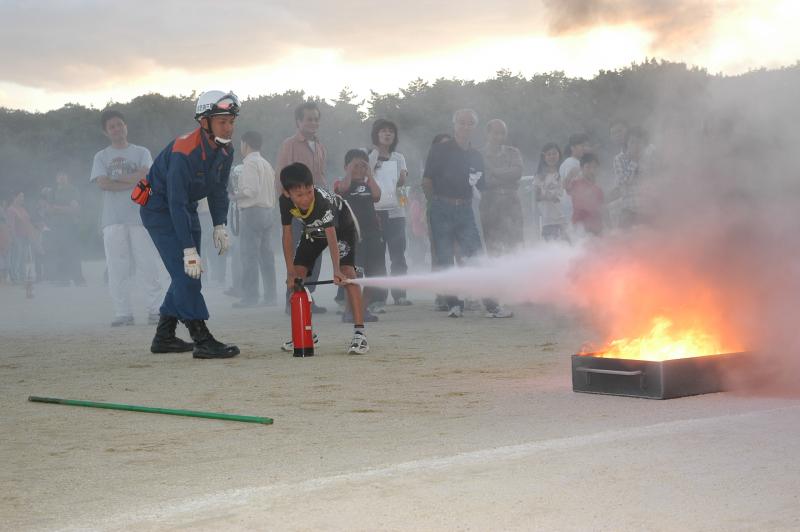 写真：消火訓練で消火器を噴射しておどろく少年