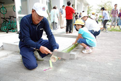 写真：竹馬作りでおじいちゃんのお手伝いをする児童