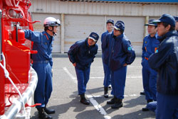 写真：尾三消防組合の消防職員からポンプの使用方法について説明を受ける団員
