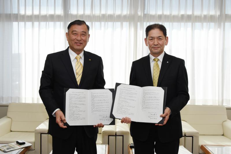 署名した協定書を手にする小野田みよし市長と西村益城町長