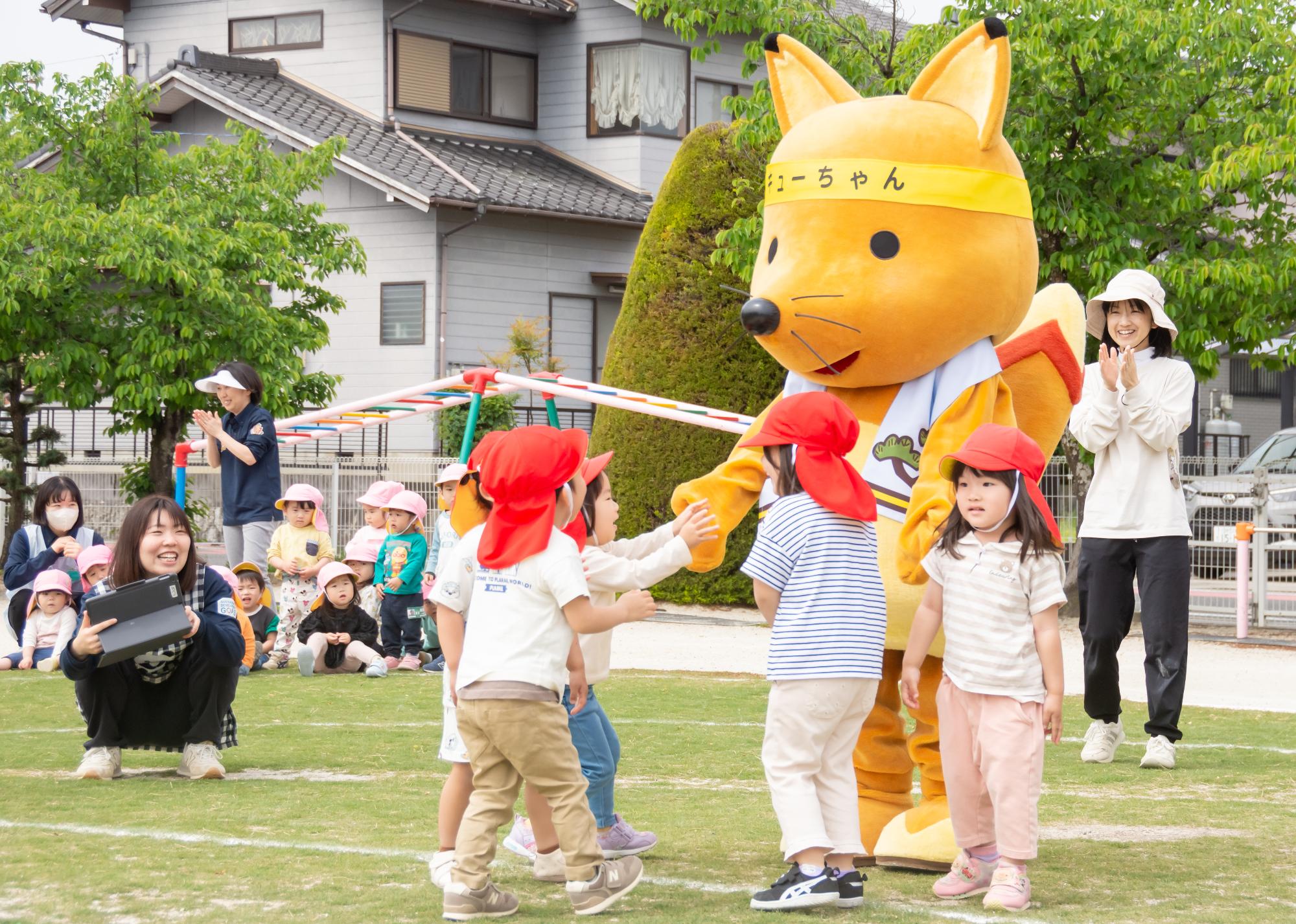 キューちゃんとハイタッチをする園児たち