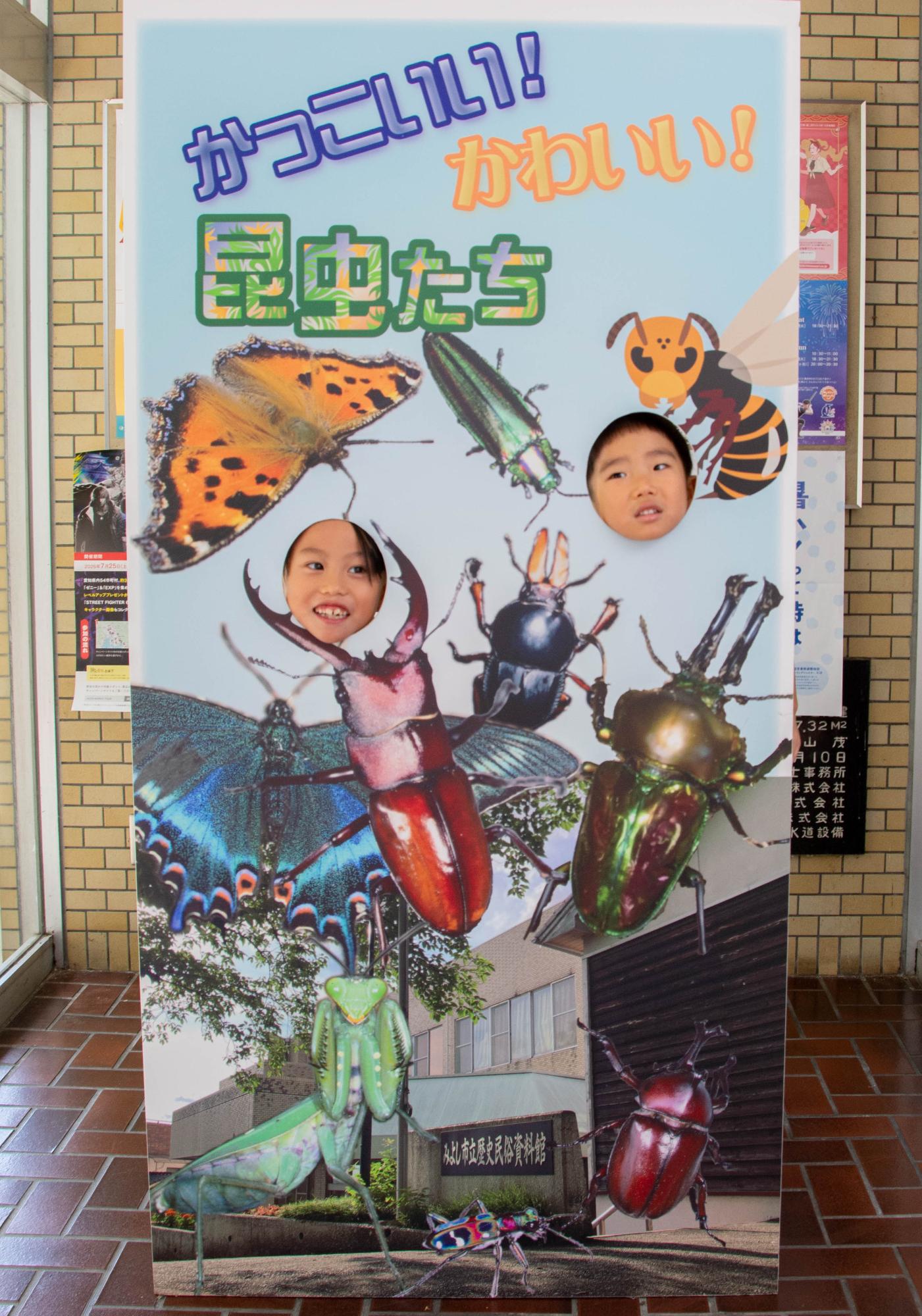 昆虫展のパネルに顔をはめるこどもたち