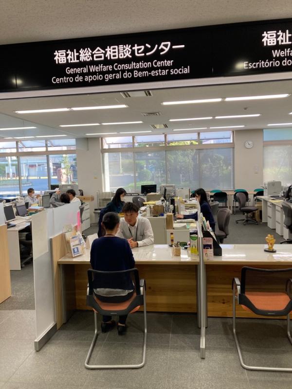 福祉総合相談センターと書かれた窓口に受付の机を間にし職員と女性が向かい合って話している写真