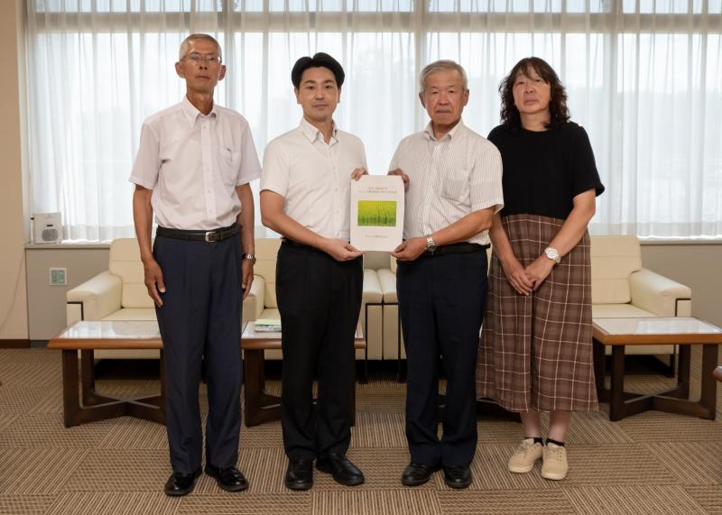 意見書を持っている小山市長と農業委員会の男性、関係者の男性と女性4人が市長公室で記念撮影を行っている写真