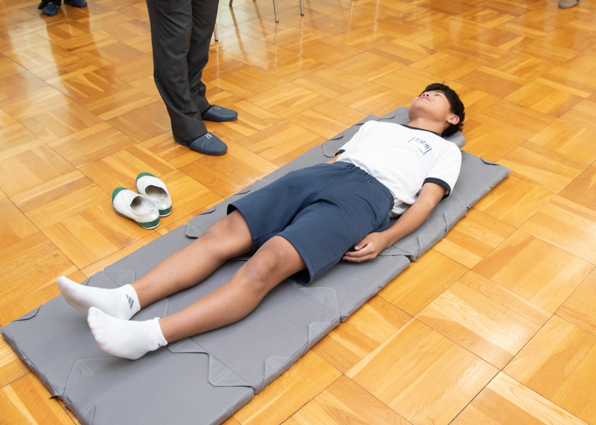 防災マットをつなげてその上で寝そべる中学生