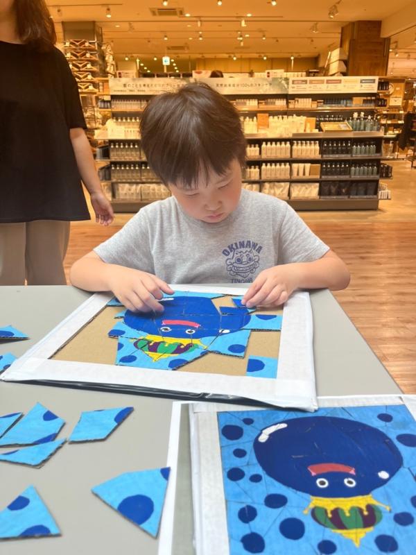 ショッピングセンター内の会場ででジグソーパズルを楽しんでいる子どもの写真
