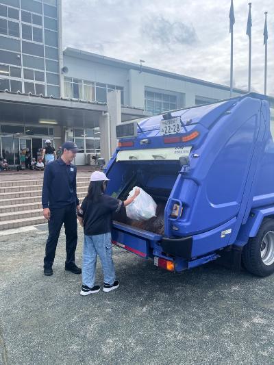 パッカー車にごみを投入する児童