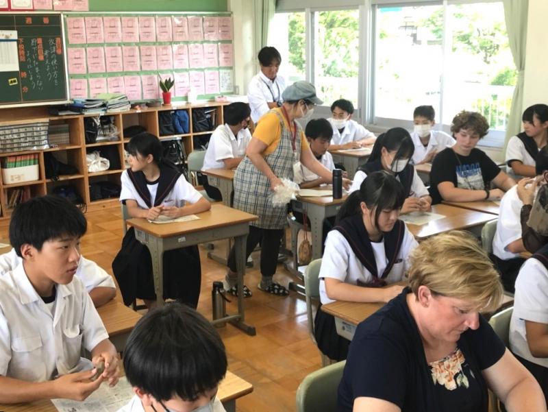 コロンバス市から来た女性や生徒が三好中学校の生徒達の間に並べられた席に座り、一緒に作業を行っている様子の写真