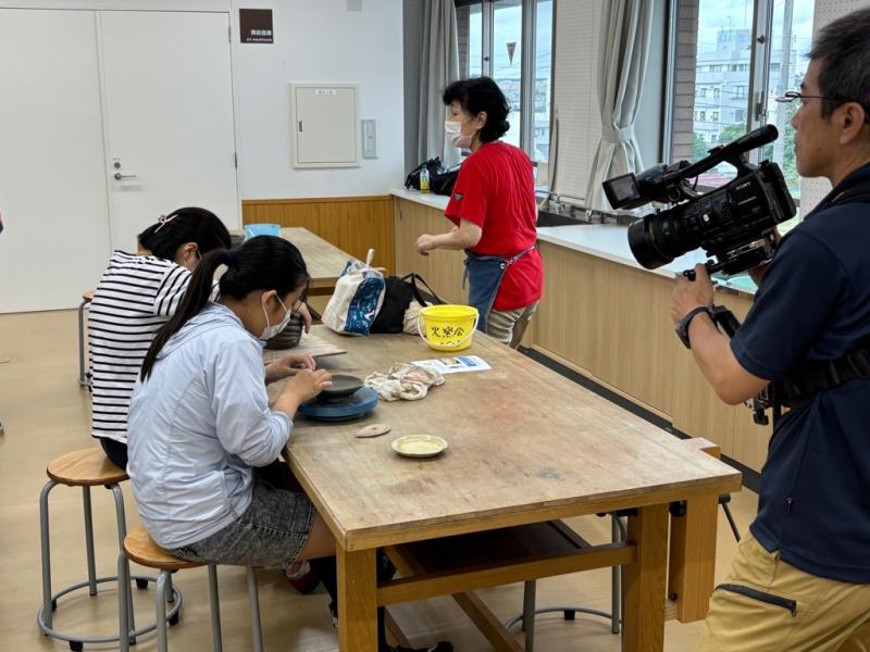 作業中の女の子を横からカメラで撮影している男性の写真
