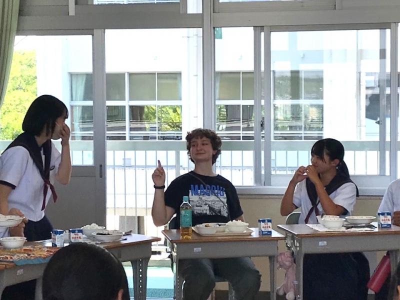 コロンバス市から来た高校生と中学生が机を並べて、楽しそうに交流をしている給食時の写真