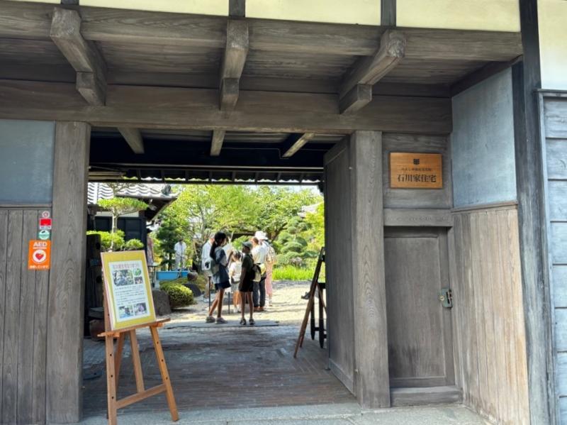 重厚な木製の門の入り口に案内看板が立てられている写真