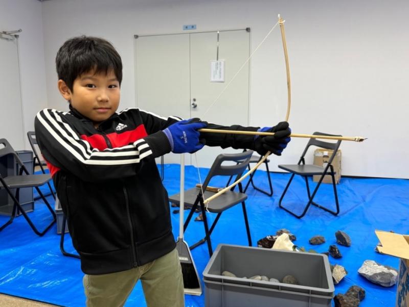 弓をひいてポーズをとっている男の子の写真