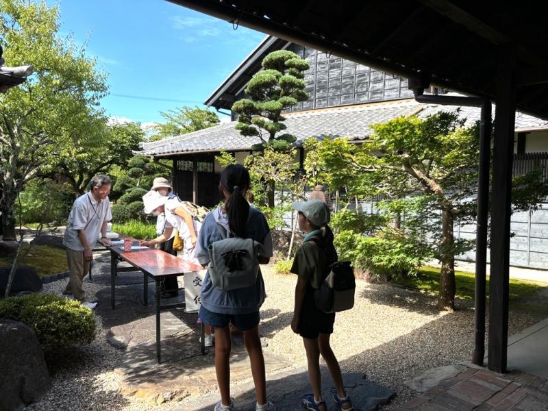 きれいに手入れされた植栽がある中庭にテーブルが置かれ、その周りに人が集まっている写真