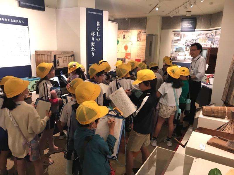 説明している職員とメモを取りながら話を聞いている児童たちの写真
