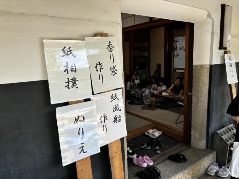 建物の入り口に貼られた、紙相撲、香り袋作り、ぬりえ、紙風船作りの張り紙の写真