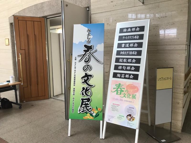 入り口に「みよし市春の文化展」と書かれた案内板と文化展の内容が書かれた案内板が並べて設置されている写真