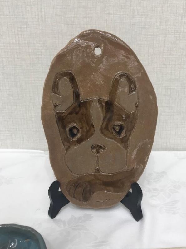 大きな茶色の石に正面を見ている犬の顔が彫られている作品をアップで写した写真