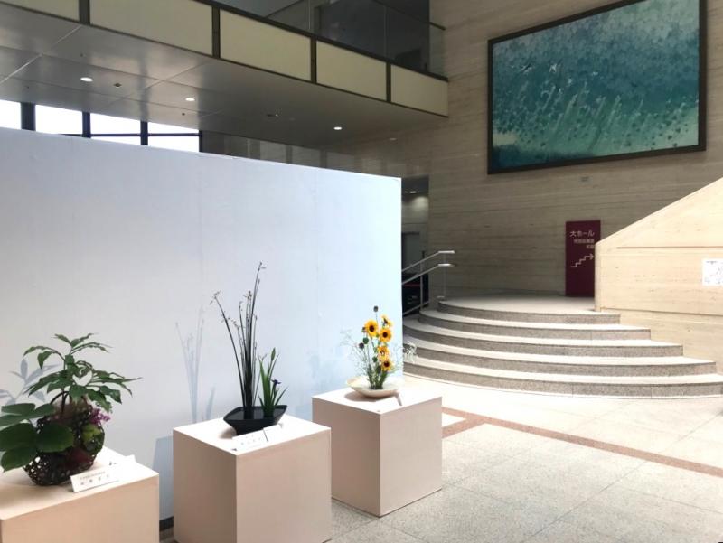 階段があるホール近くに展示されている生け花3点を写した写真