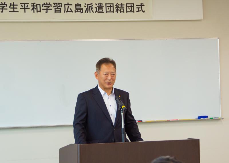 演壇でマイクを使い増岡潤一郎さんが話をしている写真