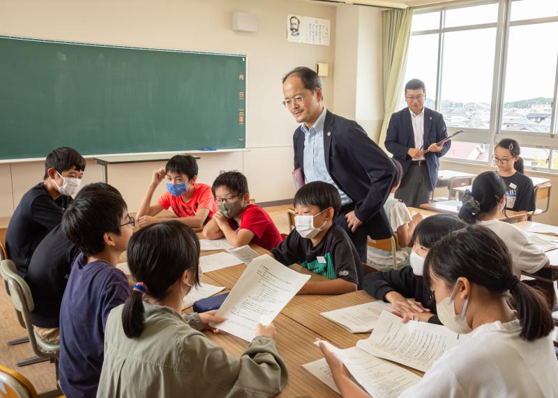 判決を出すため、裁判官役・裁判員役による話し合いを行っている生徒達を室穂高弁護士が見ている写真