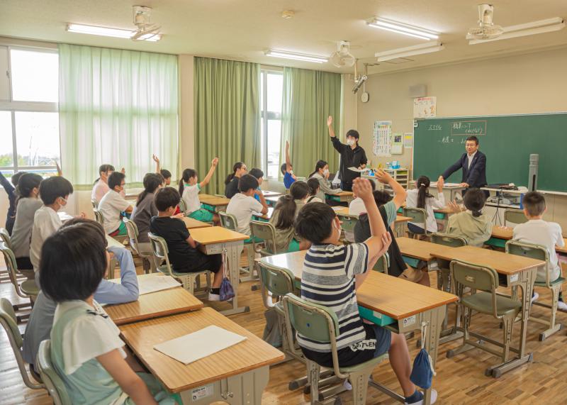 教室の前方にいる松山剛久さんに複数の生徒達が挙手をしている様子の写真