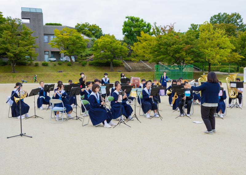 グランドにパイプ椅子が設置され、北中吹奏楽部の皆さんが演奏している様子の写真