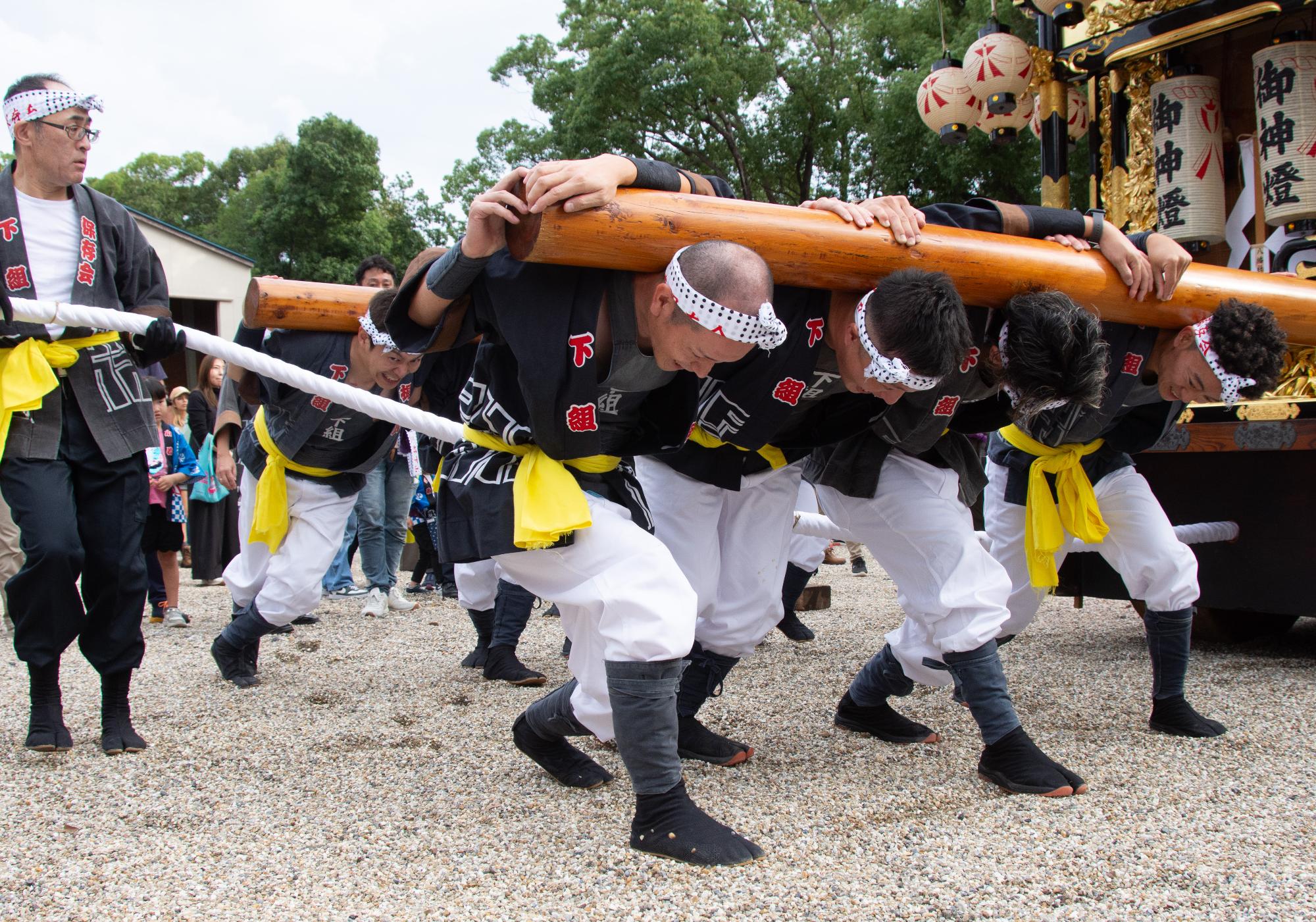 山車の方向を変えるために力を入れる担ぎ手たち