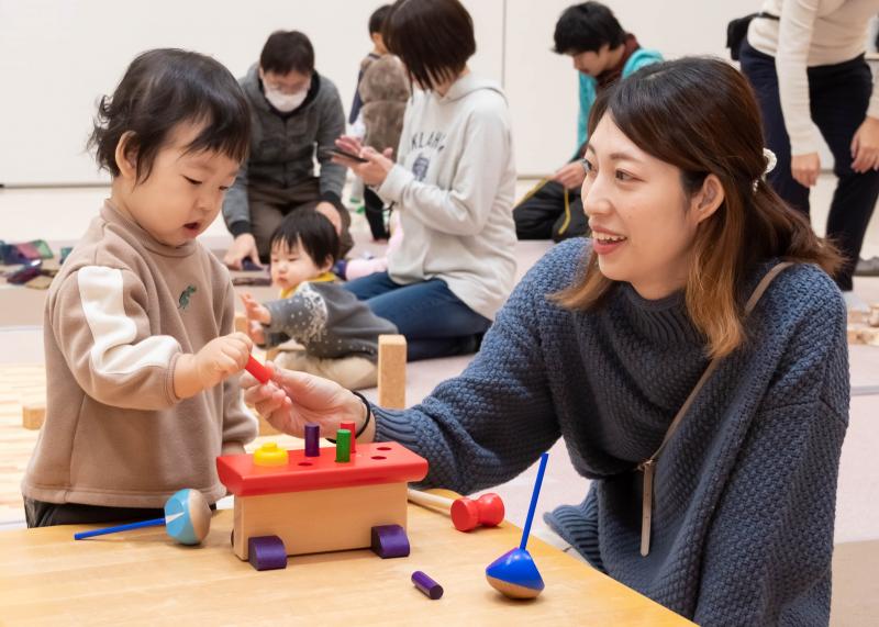 カラフルな色が付けられた木のおもちゃで遊ぶ小さな子供と母親の写真