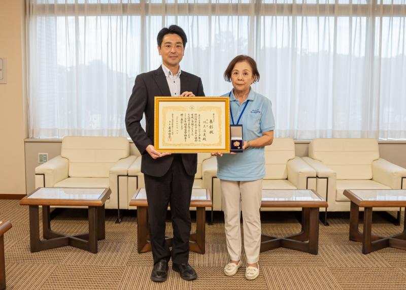 受章した川上さんと小山市長が2人で賞状を持ちながら左手にはメダルも持っている川上さんとの記念写真