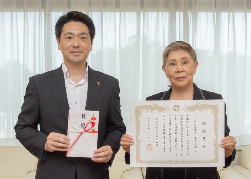 目録を市長が持ち賞状を都筑善惠代表理事が持ちながら2人で並んで記念撮影をしている写真