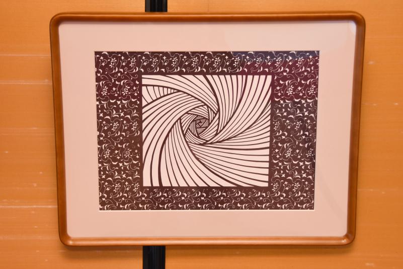 切り絵で作られた模様の作品が額に入れられて襖に掛けられている写真