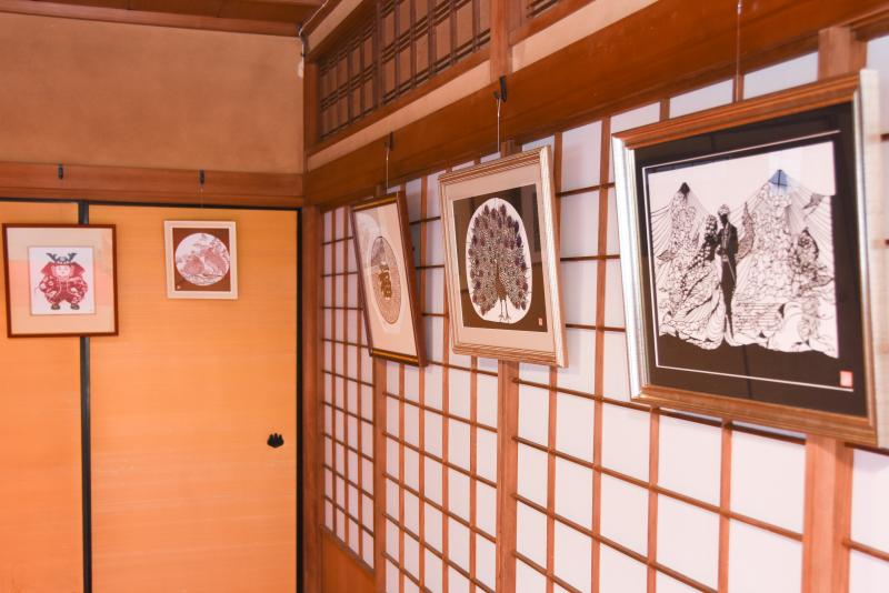 額に入れられた切り絵の作品が、座敷の襖や障子に掛けられて展示してある写真