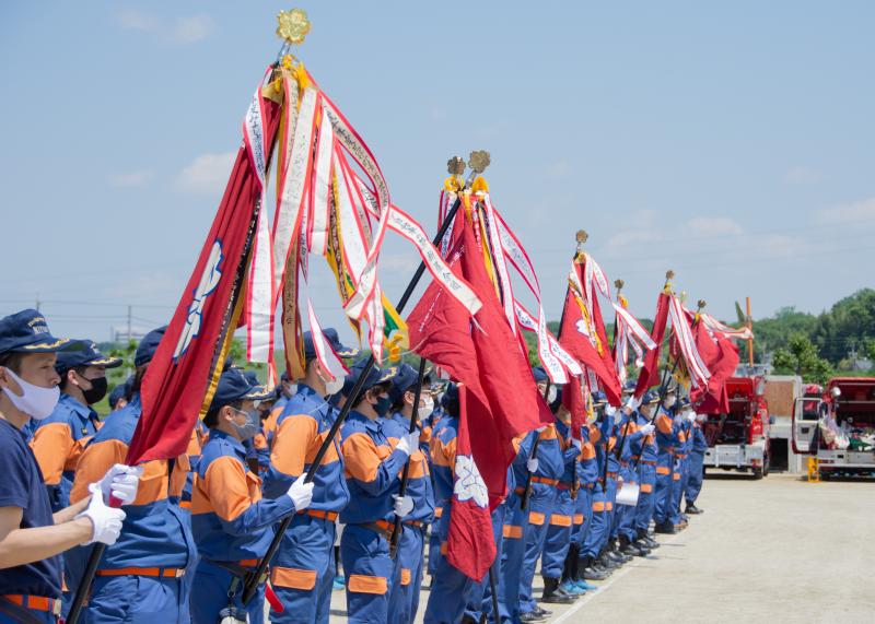 大会に出場した12分団が各分団の旗を掲げ、横一列に整列している写真