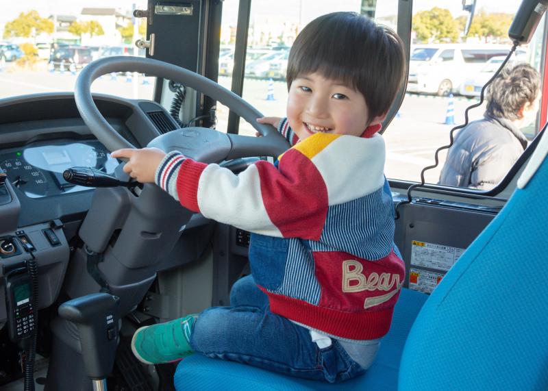 バス乗車体験で運転手席に座って笑顔でハンドルを握っている男の子の写真