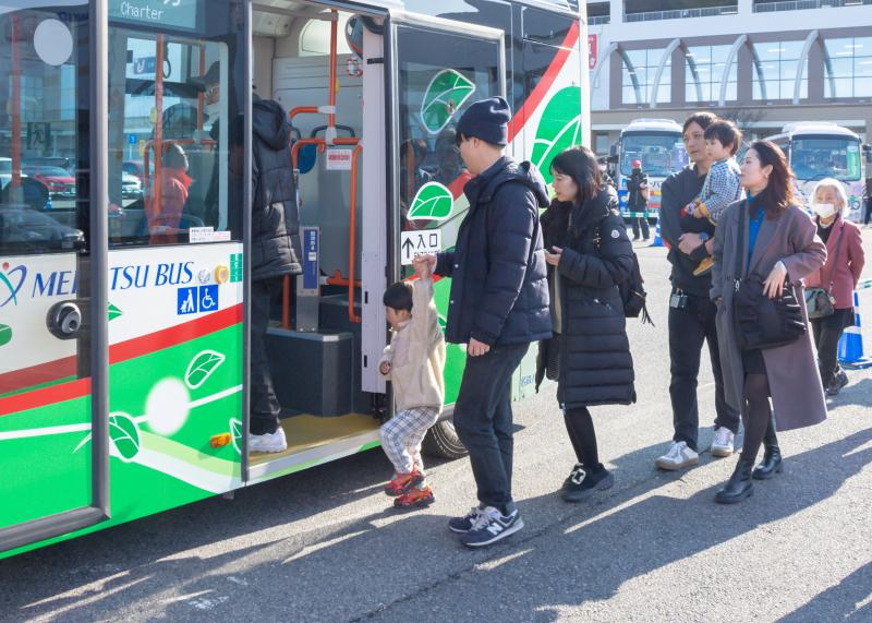 後方の入口からEVバスに乗車する参加者たちの写真