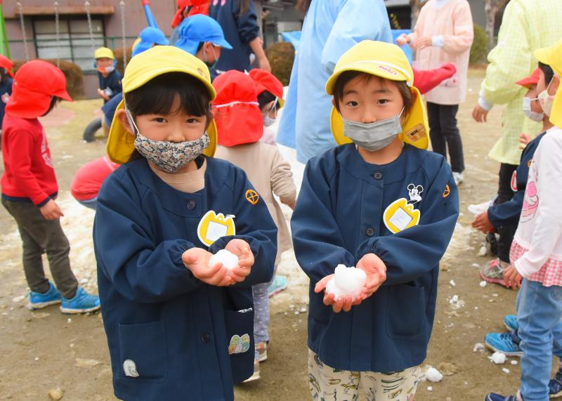 男の子の園児が両手に雪をのせ、カメラに見せている写真