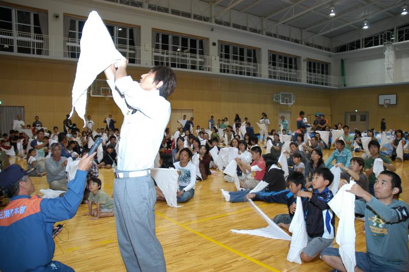 写真：三角巾を使って包帯を巻く練習をする参加者