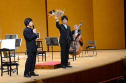 写真：個性的な楽器の形状の理由を楽しく説明する田久保さん
