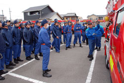 写真：消防署員からポンプ車の扱い方を習う団員たち