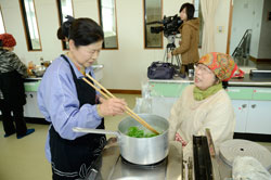 【写真】大根の葉を鍋に入れて湯通しする参加者