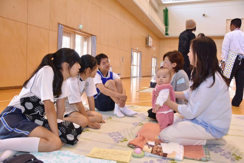 赤ちゃんの保護者の話を熱心に聞く生徒たち