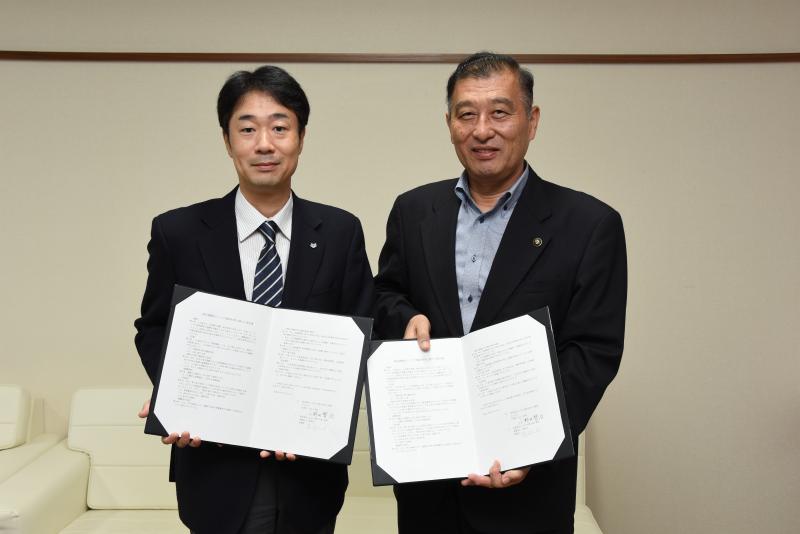 協定書を手に笑顔を見せる小野田市長と篠﨑理事長