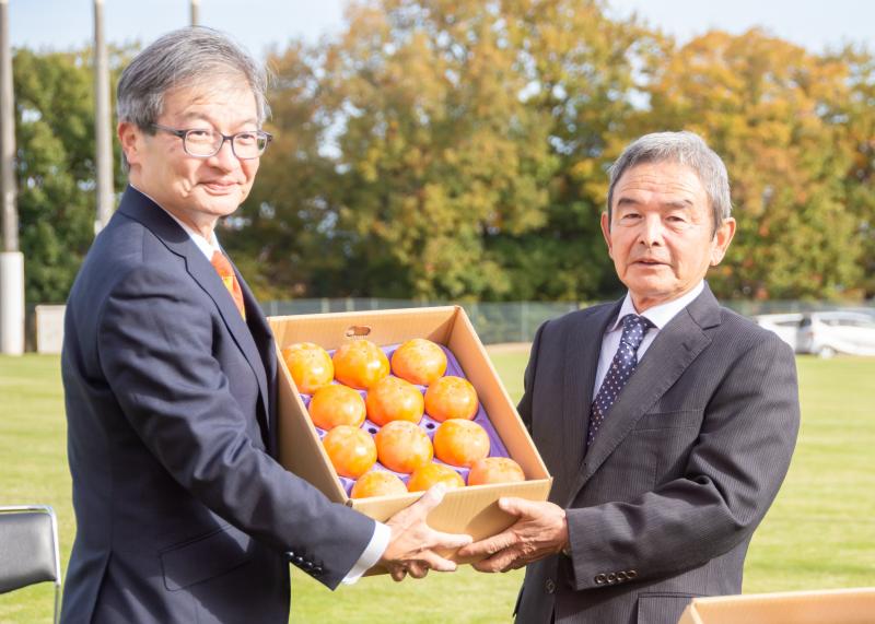 小野田果樹組合長が小西代表取締役社長へ柿を手渡している