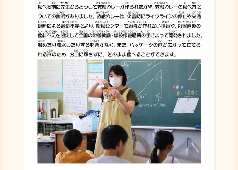 黒板の前に立った先生が救給カレーを手に持ち、生徒たちに説明をしている写真