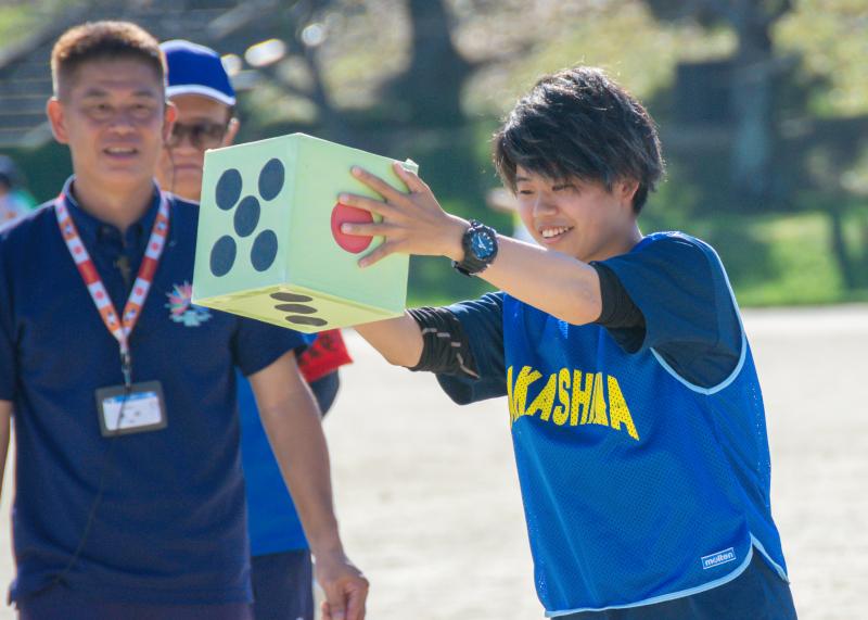 大きなさいころを両手で持っている選手の写真