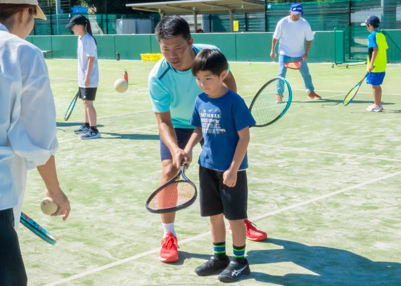 ソフトテニス体験に参加している男の子と講師の浅川陽介さんの写真