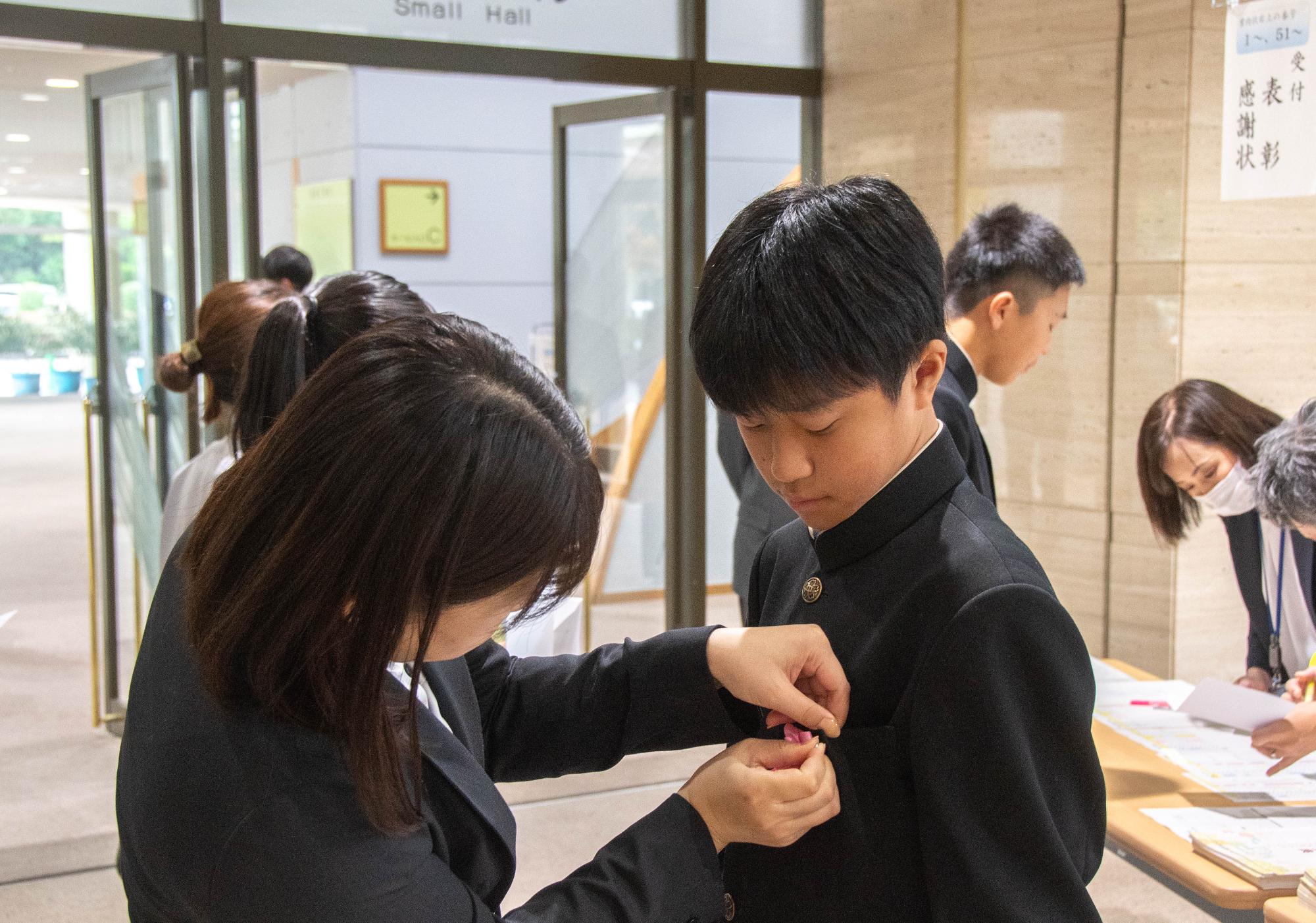 受付で花を胸につけている様子