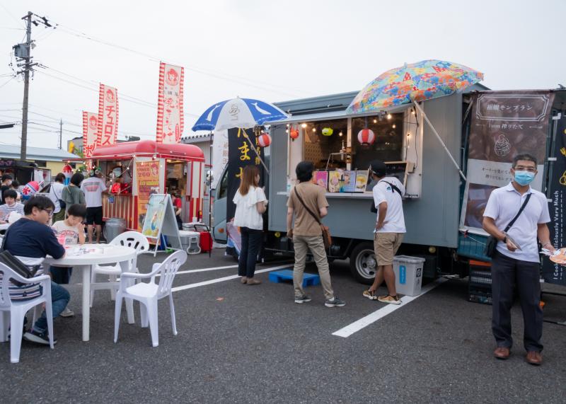 キッチンカーが並ぶお店で商品を待っているお客さんの写真