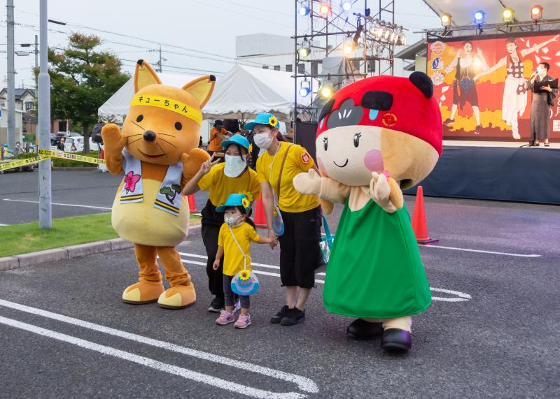 みよし市健康づくり大使キューちゃんと安全安心キャラみよ獅子ちゃんを両脇に女性2人と小さな女の子が記念撮影している写真